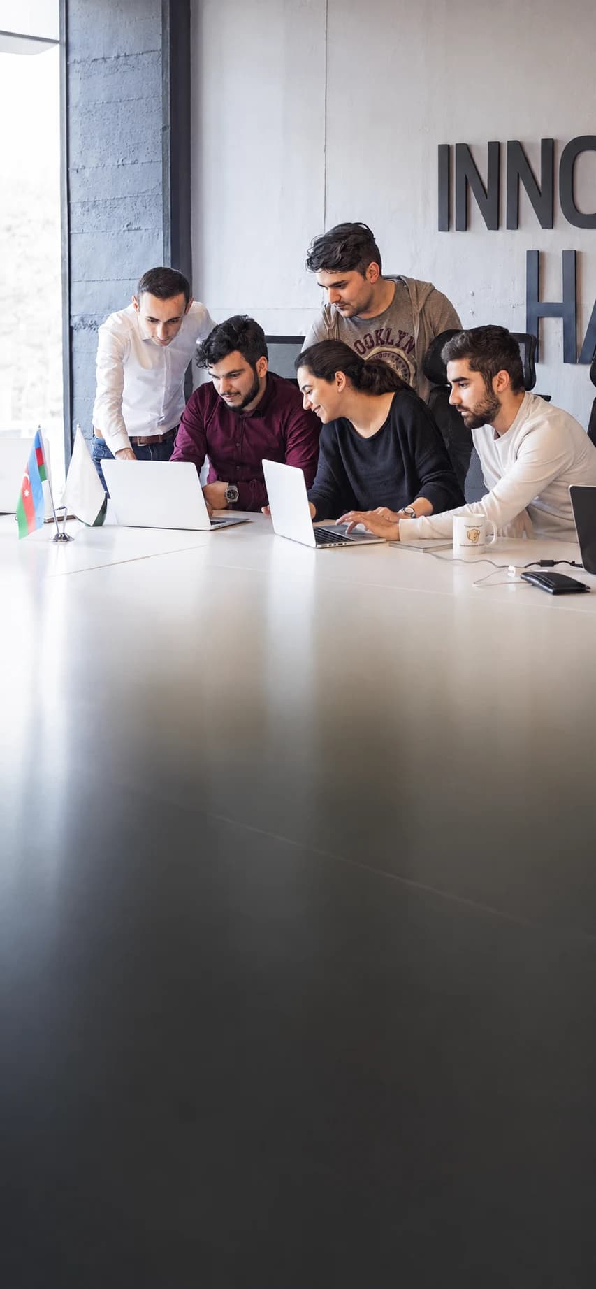 Five colleagues working together around laptops
