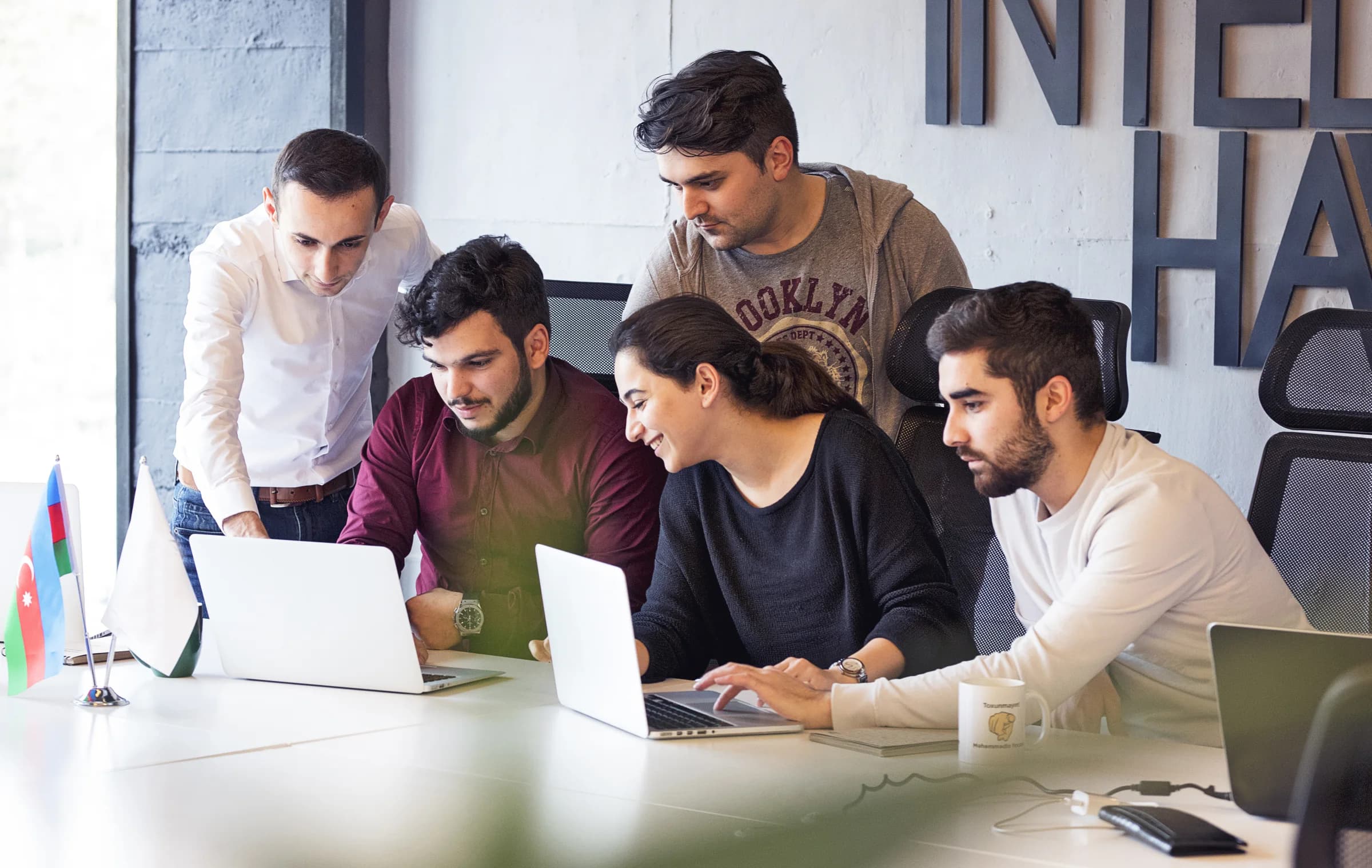 Five colleagues working together around laptops